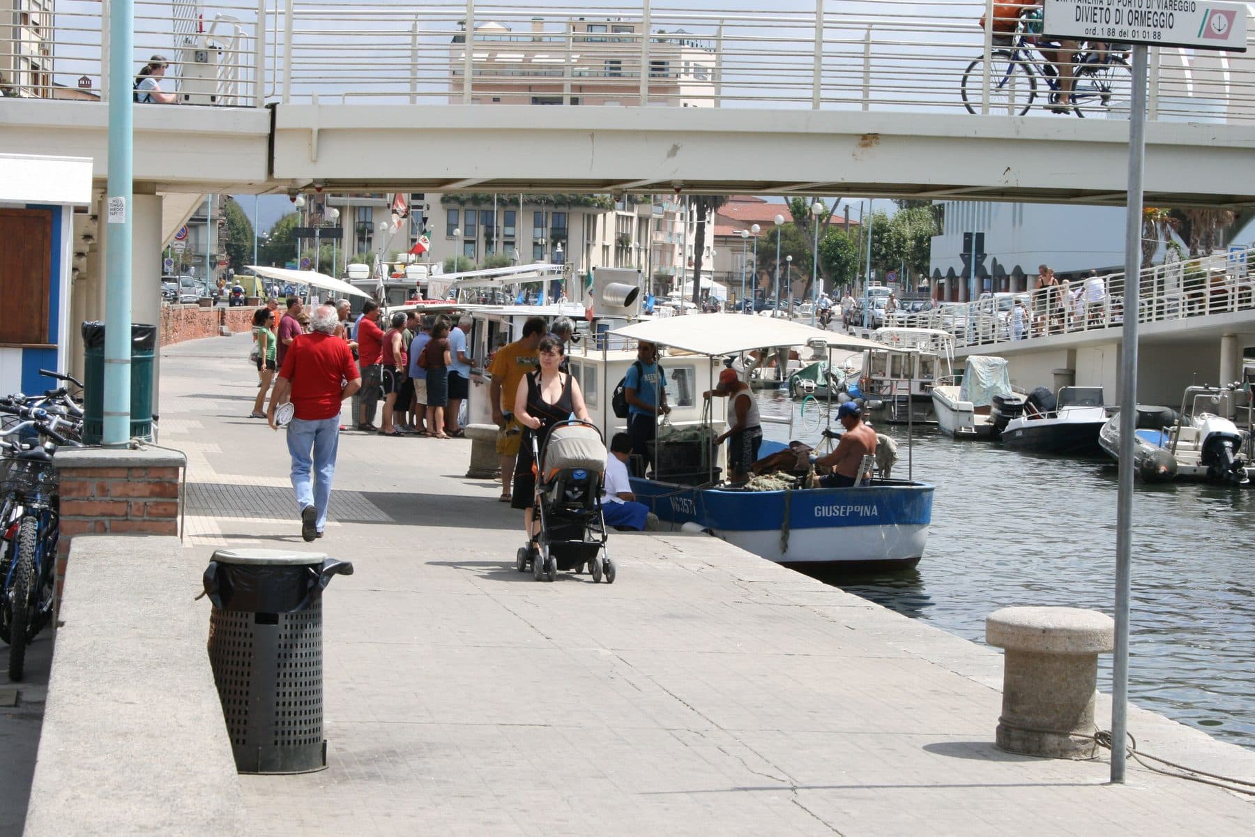 Pescatori vendono il pescato direttamente dalla barca sul porto canale di Viareggio, con i clienti in fila sulla banchina